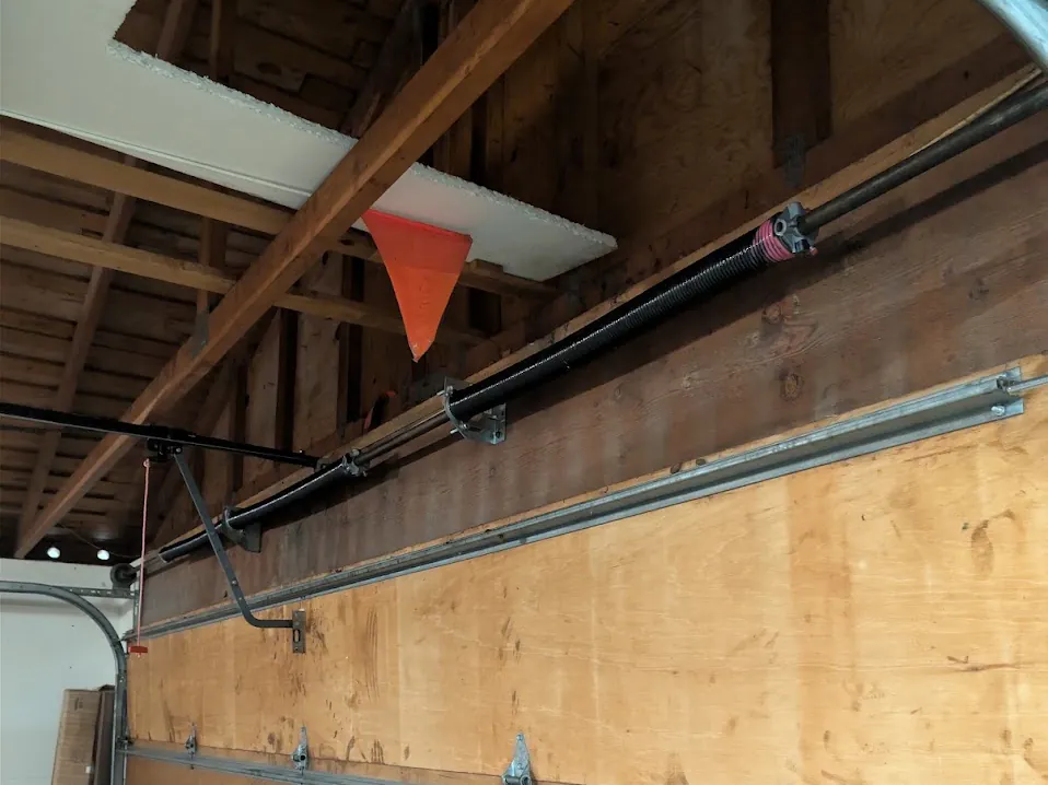 A single torsion spring on the shaft above an older wood sectional garage door.