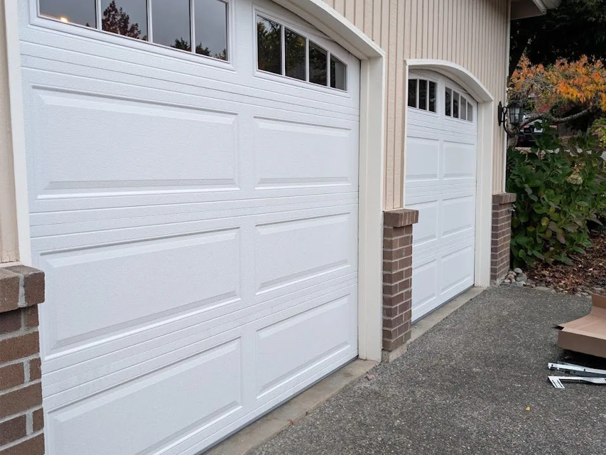 White garage door with an arched window insert and brick column surround