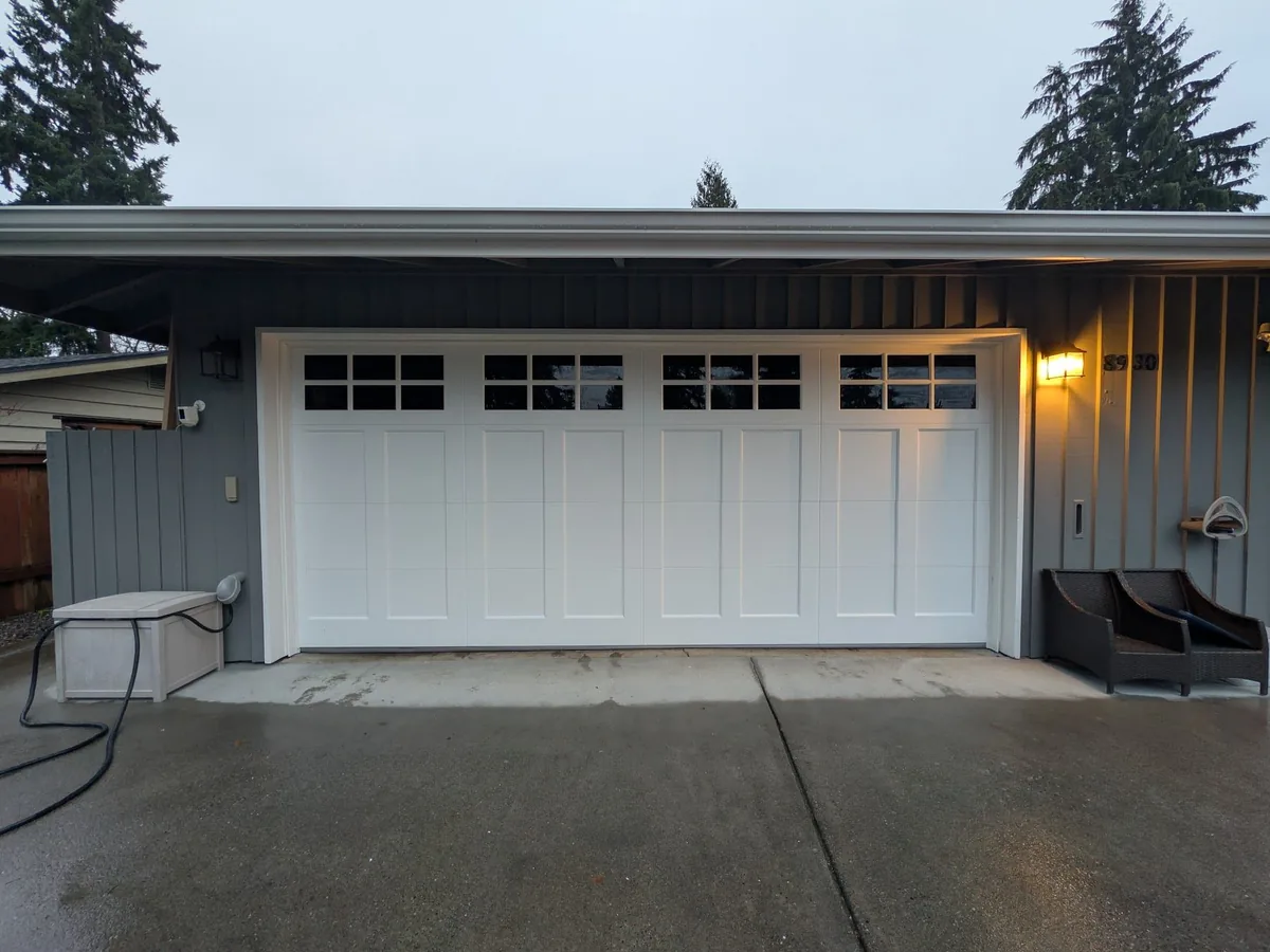 White carriage style garage door with divided lite windows photographed in evening light