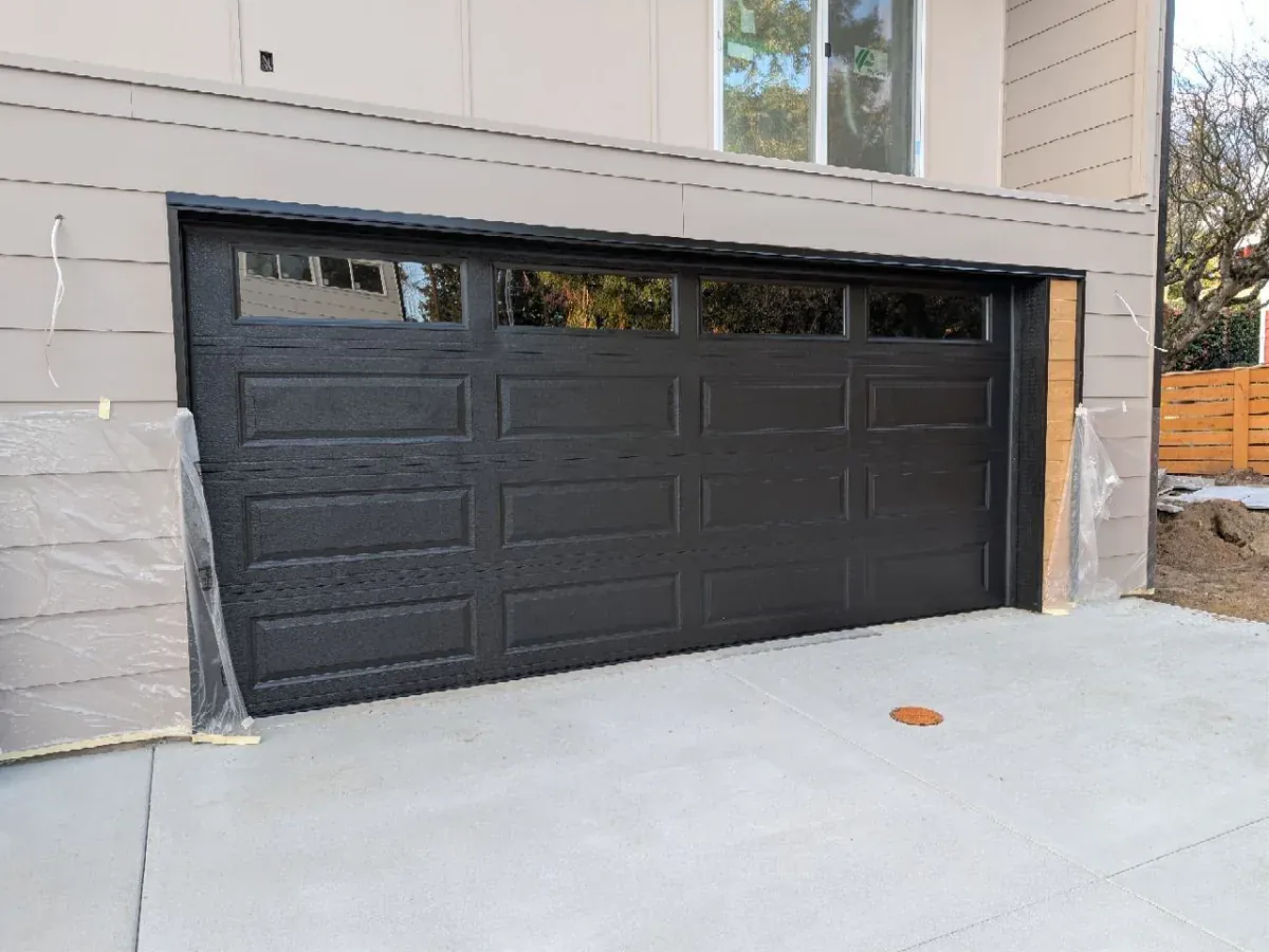 Dark bronze long panel garage door with a row of windows across the top