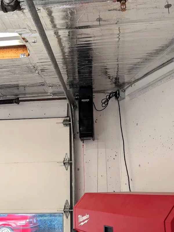 Close view of a LiftMaster jackshaft opener anchored to the concrete wall beside a garage door